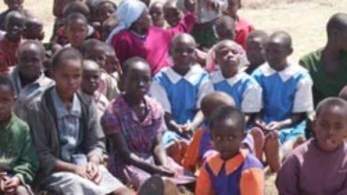 Enfants assistant à un cours sous un arbre, dans un camp de déplacés