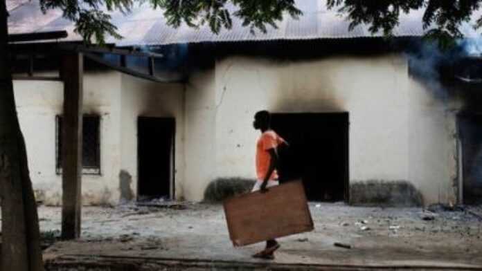 Un habitant devant un bâtiment incendié