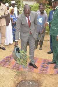 Le ministre de l'Environnement du Sénégal, Abdou Karim Sall, debout, sur une natte pour planter un arbre