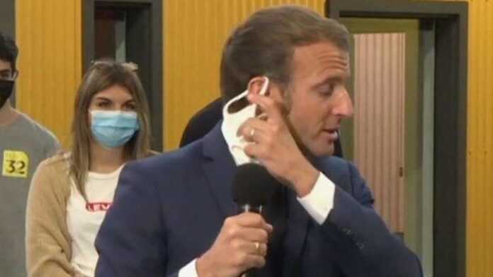 Le Président Emmanuel Macron en train d'ôter son masque