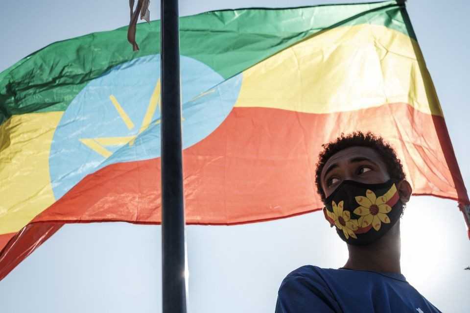 A youngster stands below an Ethiopian national flag during a blood donation rally organised by the city administration of Addis Ababa, in Addis Ababa, on November 12, 2020. - Hundreds of Ethiopians gathered in the capital on November 12, 2020, to donate blood for troops fighting in the northern Tigray region, as officials tried to rally support for a conflict Prime Minister Abiy Ahmed said was going his way. (Photo by EDUARDO SOTERAS / AFP)